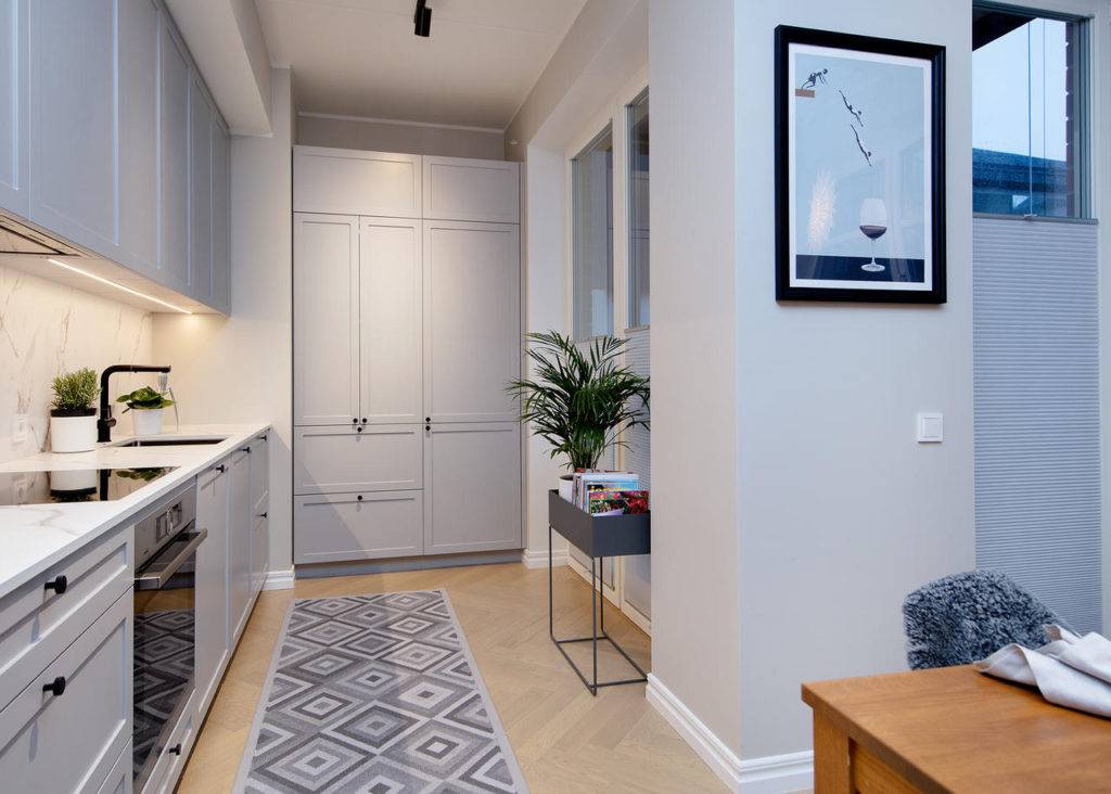 Перенос кухни в коридор - особенности дизайна кухни, совмещенной с прихожей; пюсы и минусы такой планировки; выбор отделочных материалов для пола, стен и потолка; как зонировать пространство - физическое зонирование, световое, контрастное