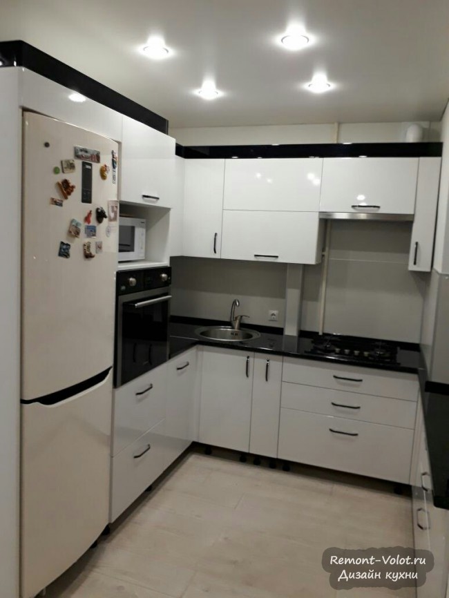 Дизайн белой кухни 5 кв.м с черной столешницей и холодильником в нише