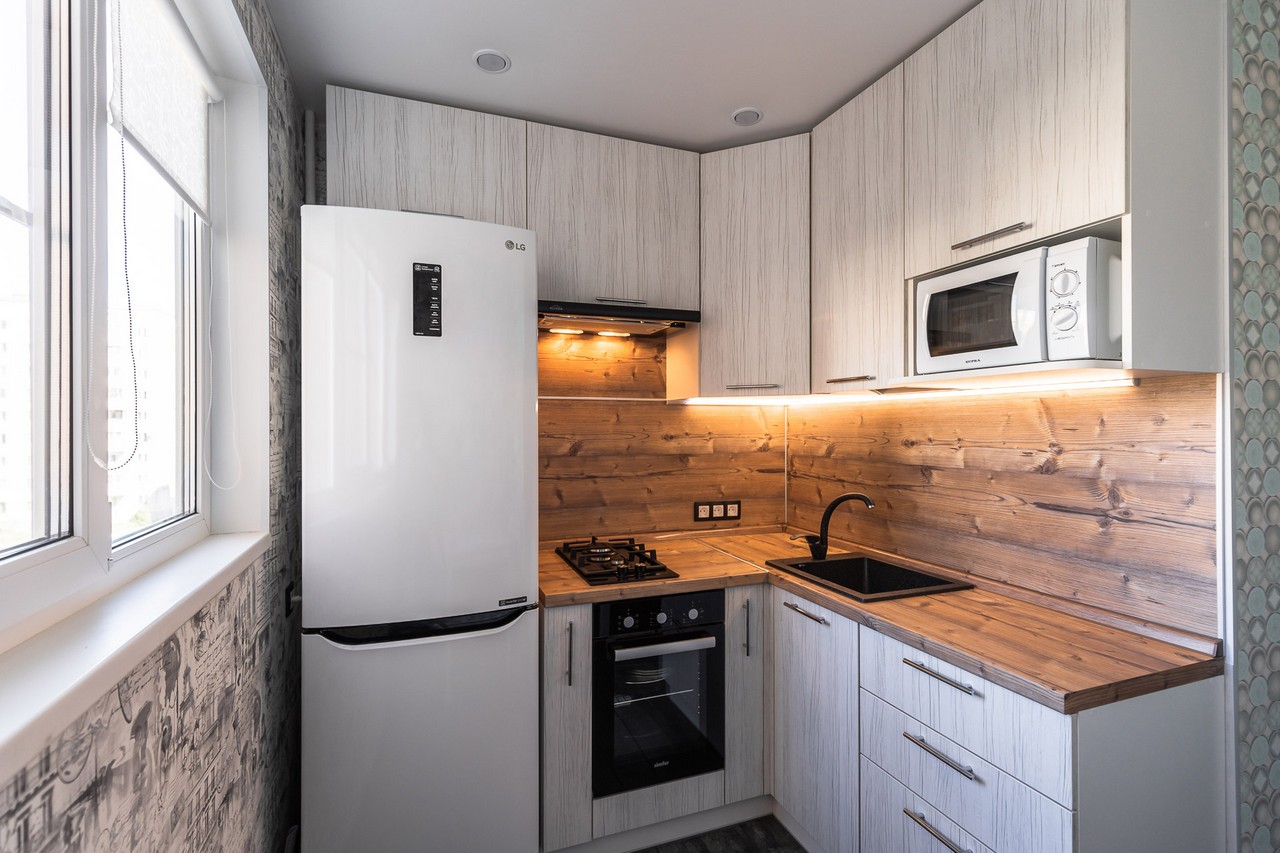Проект белой кухни 7 кв м с деревянной столешницей и холодильником напротив гарнитура
